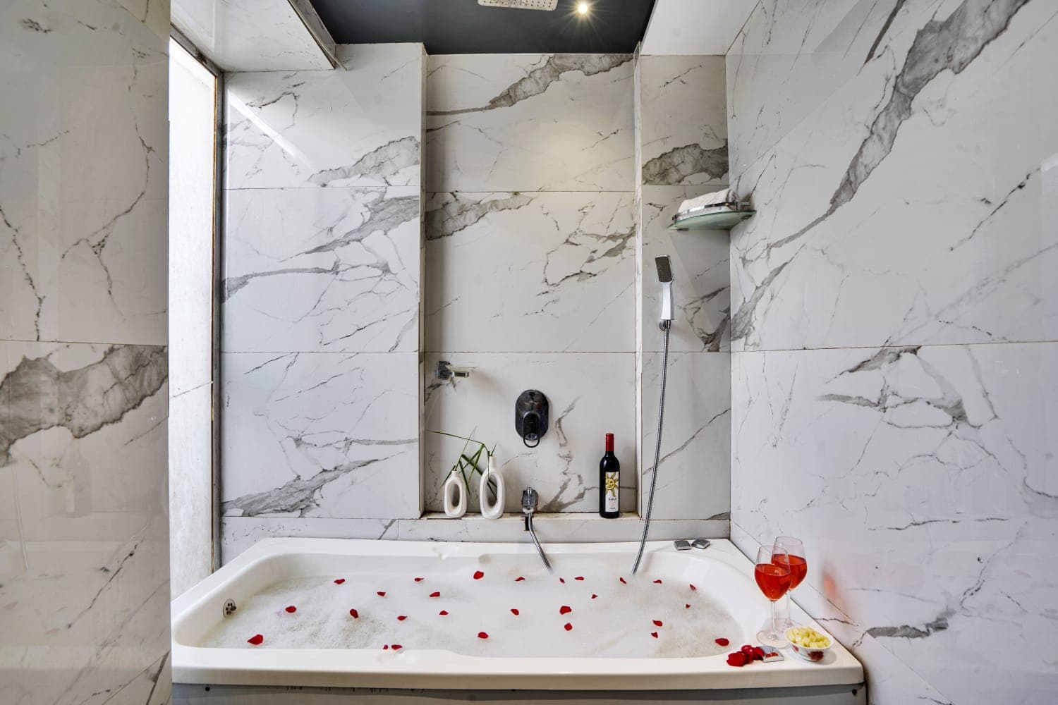 A marble bathroom with a rose-petal bath drawn and wine poured